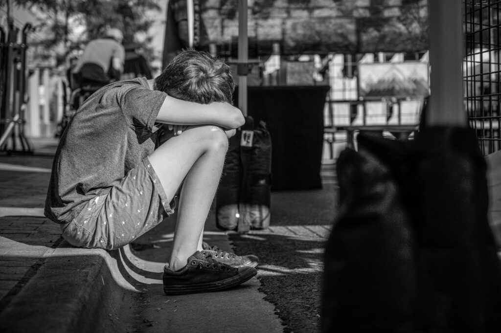 monochrome photo of person sitting on curb