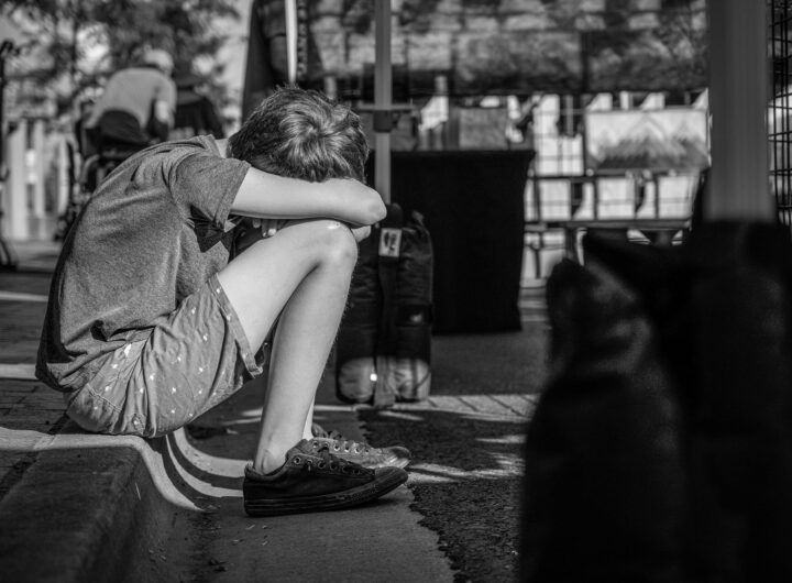monochrome photo of person sitting on curb
