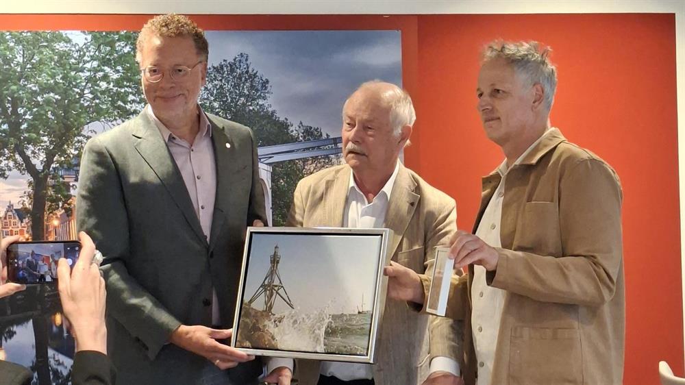 Wethouder Dennis Boutkan ontvangt van Fred Veerman en Marco Wohlken op symbolische wijze het idee voor het burgerinitiatief voor de wisselexpositieruimte.