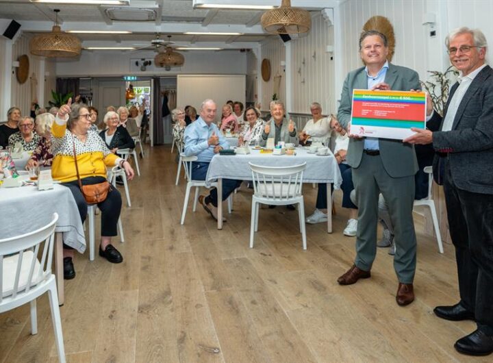 Wethouder René Assendelft feliciteert Bridgeclub Never Down ’76 in Hoorn met het 50-jarig jubileum en een Eenhoornzegel.