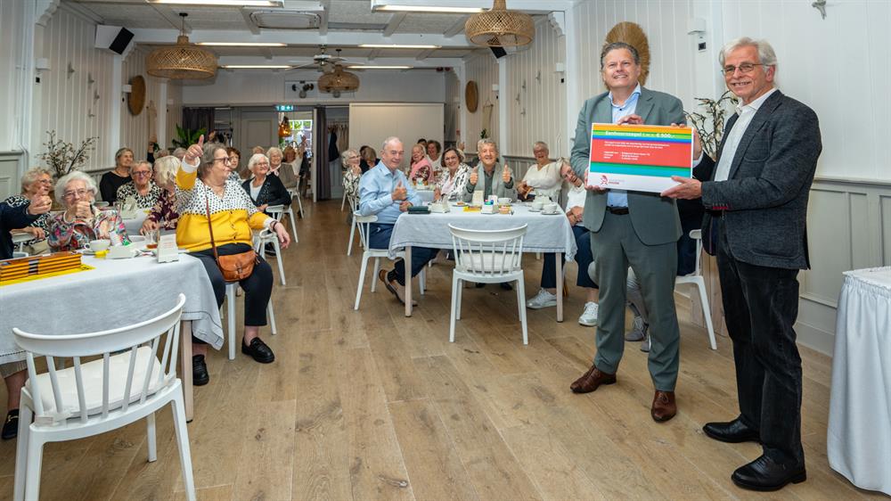 Wethouder René Assendelft feliciteert Bridgeclub Never Down ’76 in Hoorn met het 50-jarig jubileum en een Eenhoornzegel.